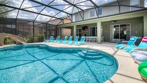 A swimming pool with a glass roof, surrounded by lounge chairs and a slide. - The Minions Mansion 6br Resort Pool Home By Disney (Kissimmee)