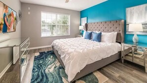 A bedroom with a bed, a ceiling fan, a window, and a blue accent wall. - The Minions Mansion 6br Resort Pool Home By Disney (Kissimmee)