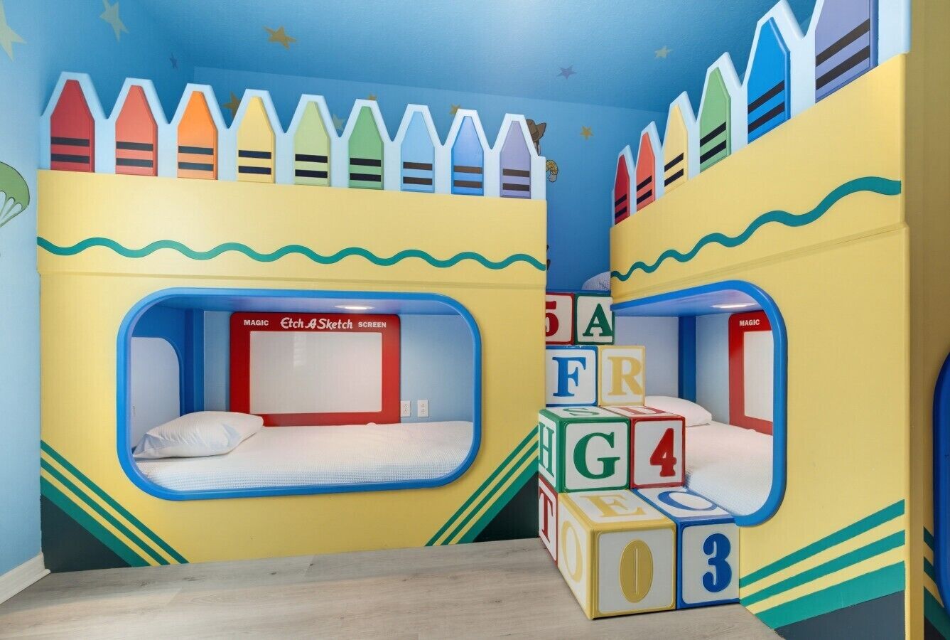 Ein Kinderzimmer mit Etagenbetten, einer Spielecke mit Buchstabenblöcken und einer Zauber-Zeichenschreibtischplatte.