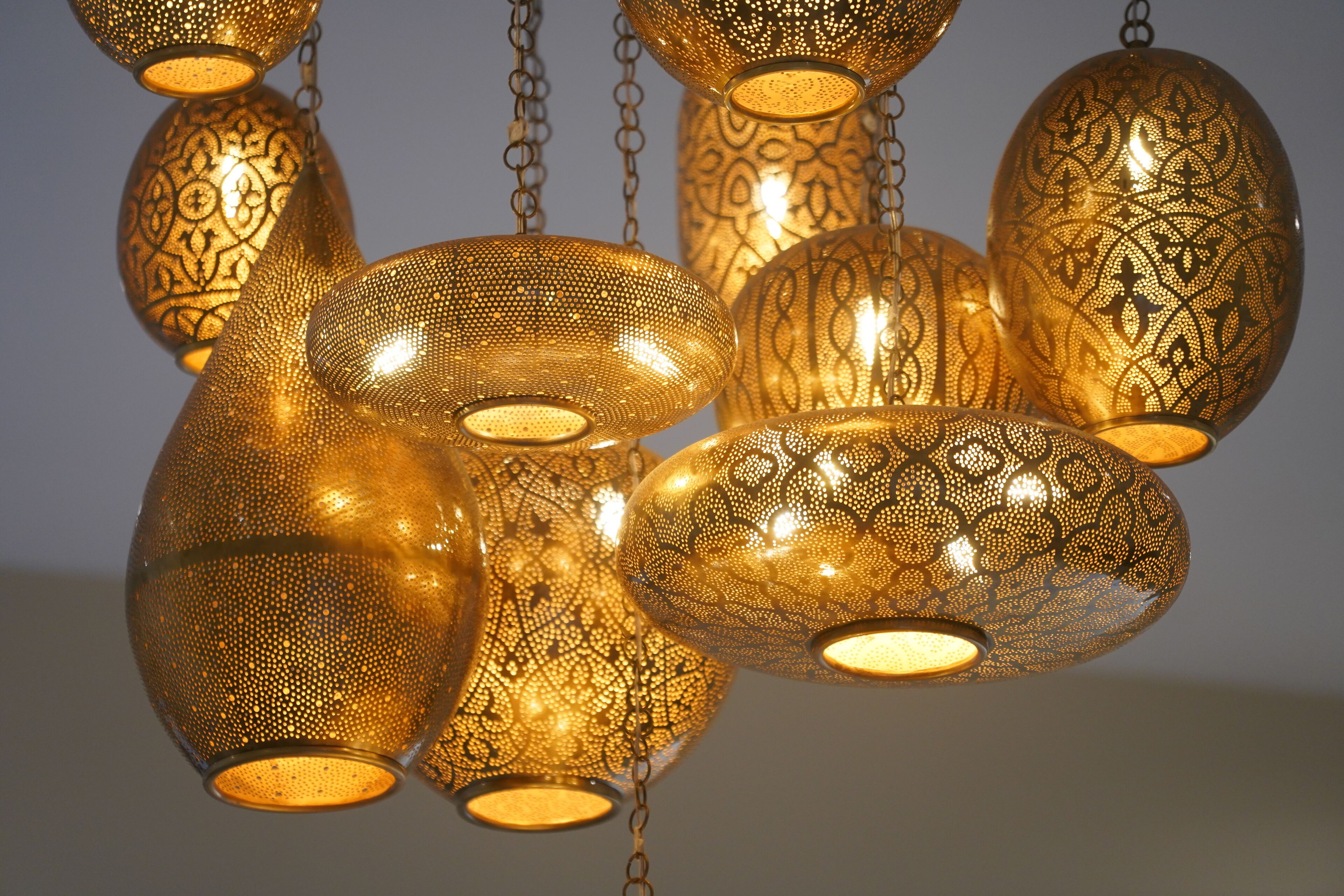 A collection of ornate, patterned hanging lamps with a warm glow.