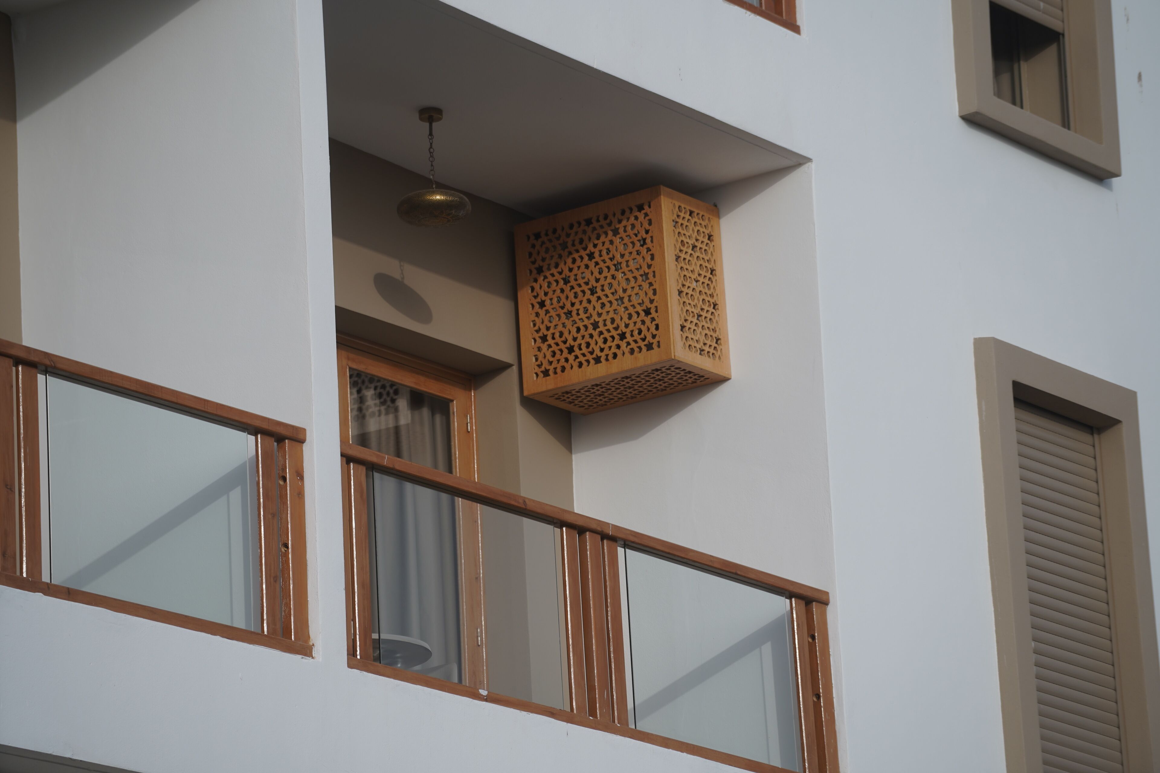 A balcony with wooden railings, a hanging light fixture, and a wooden lattice box.