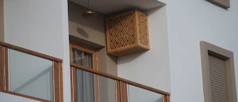 A balcony with wooden railings, a hanging light fixture, and a wooden lattice box.