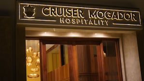 A sign for "Cruiser Mogador Hospitality" with a crown emblem and illuminated lettering. - Cruiser Mogador Hospitality (Essaouira)