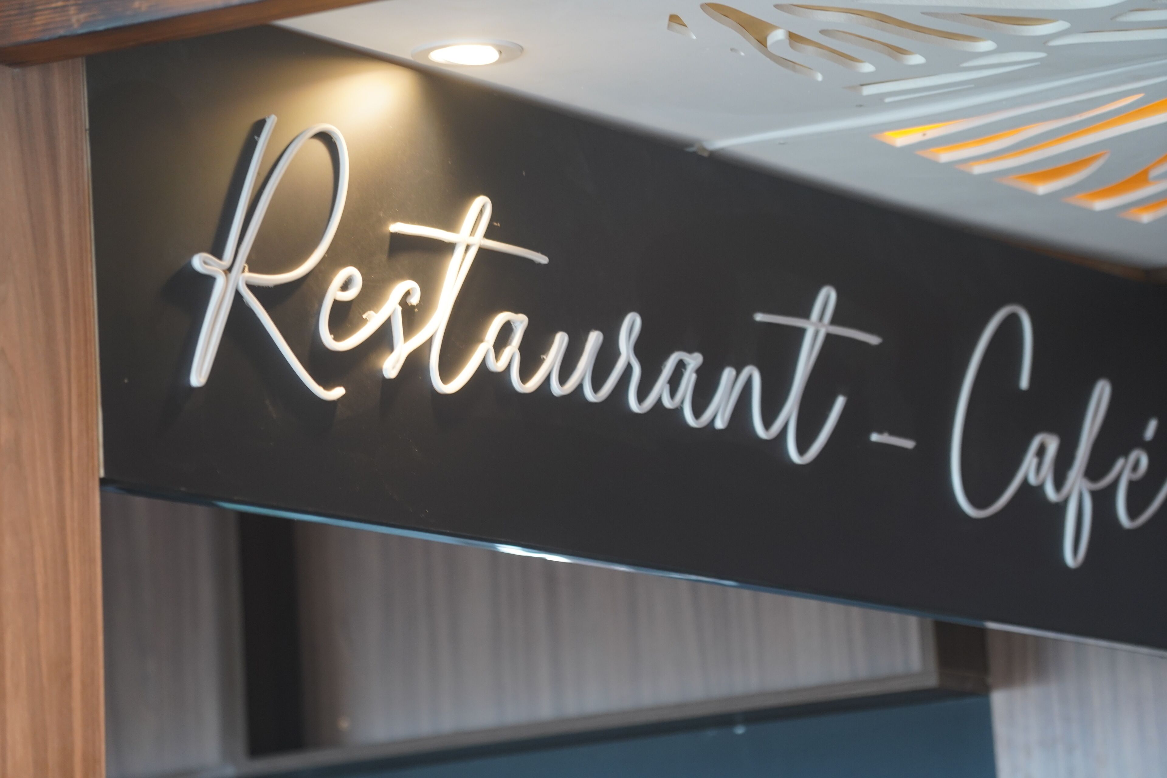 Een bord met de tekst 'Restaurant - Café' in sierlijke letters.