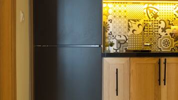 A kitchen with a black refrigerator, wooden cabinets, and a patterned backsplash.