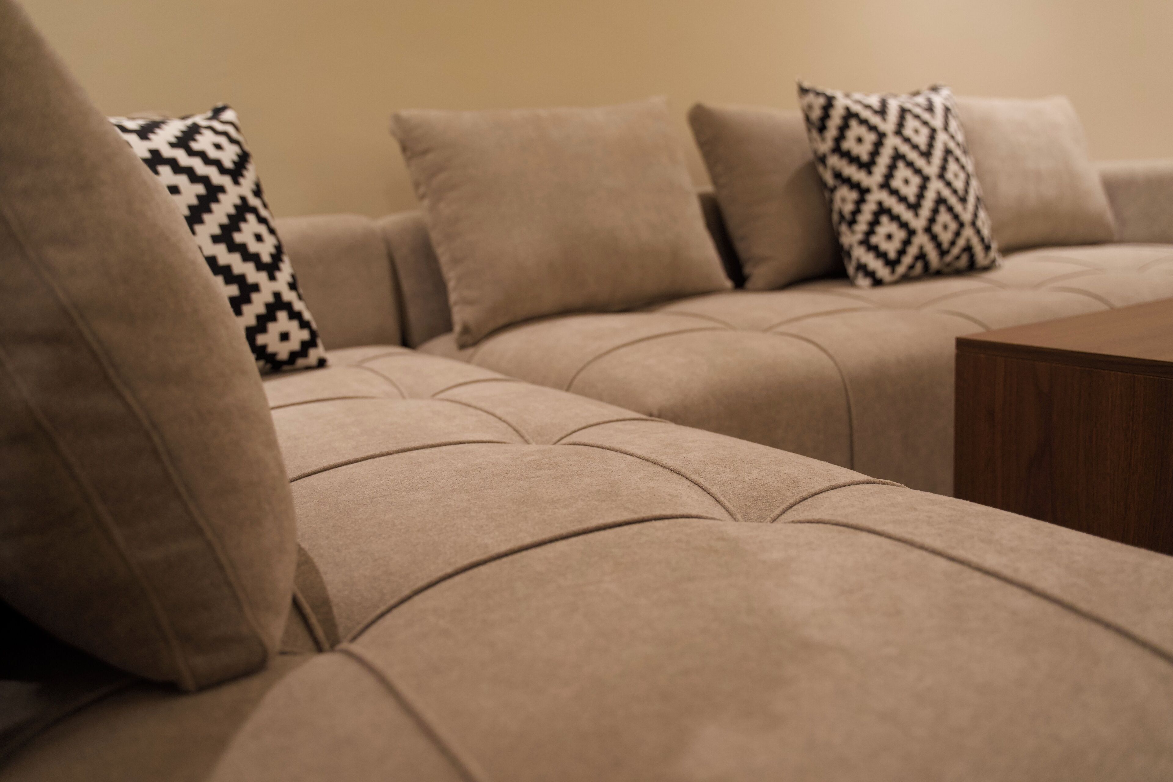 A beige sectional sofa with patterned throw pillows.