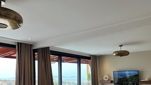 A modern living room with a sectional sofa, a wooden coffee table, and a flat-screen TV mounted on the wall. - Cruiser Mogador Hospitality (Essaouira)
