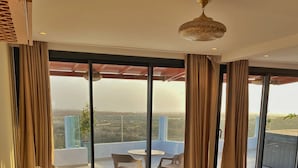 A modern living room with a sofa, a coffee table, and a view of a balcony with a table and chairs. - Cruiser Mogador Hospitality (Essaouira)