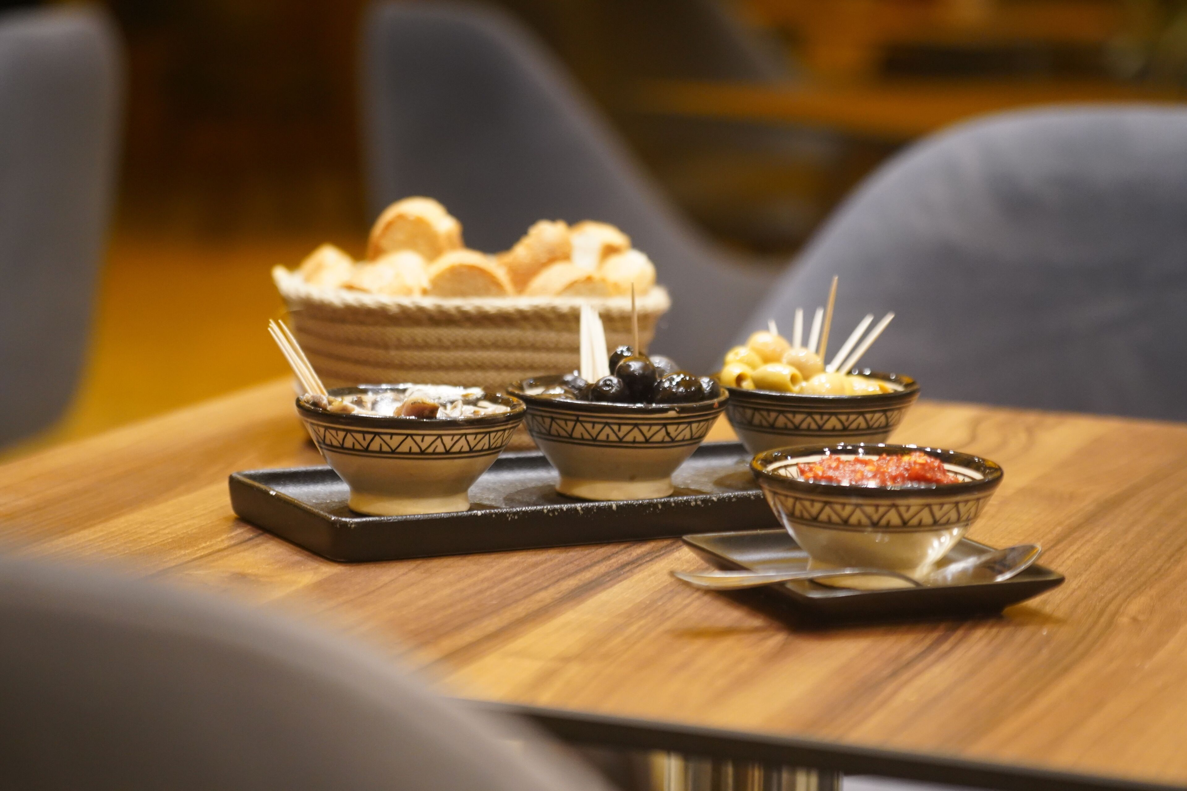 A tray with four bowls of food on a wooden table.
