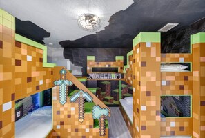 Une chambre avec des lits superposés décorés sur le thème de Minecraft, une fresque murale et un luminaire au plafond.