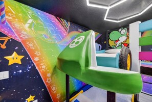 Ein farbenfroher Spielbereich mit einer grünen Rutsche und einer Schaukel aus einem Reifen.