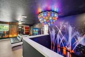 Una habitación con piscina, un sofá y una pared con una lámpara de colores.