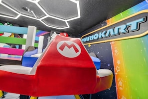 Mario Kart -teemalla sisustettu alue, jossa on punainen istuin ja seinä, jossa on Mario Kart -logon kuva.