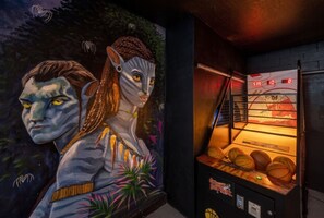Una habitación con un mural, una máquina de baloncesto recreativa y un marcador.