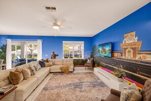 A living room with a sectional sofa, a coffee table, a TV, and a decorative wall mural.