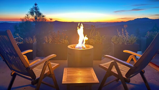 An outdoor seating area with a fire pit, two chairs, and a table.