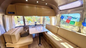 A cozy RV interior with a dining area, seating, and a view of the outdoors.