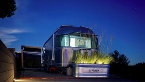 A camper van parked at night with a planter of grass in front.