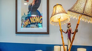 A framed movie poster of 'King Kong' on a wall, a decorative lamp with two lampshades, and several candles on a table. - Hilltop Oasis w/Pool, Hot Tub, Fire Pit + Views (Dripping Springs)