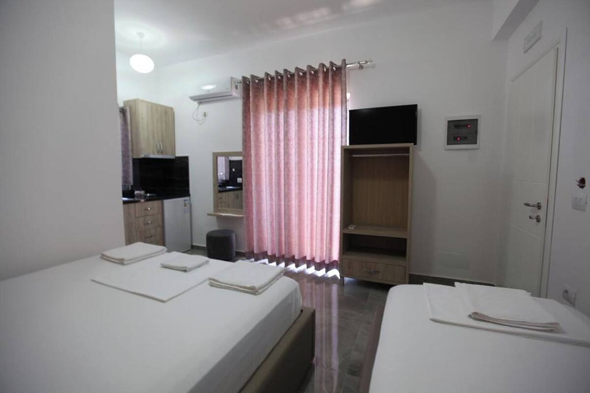 A hotel room with two beds, a television, a wardrobe, and a mirror.