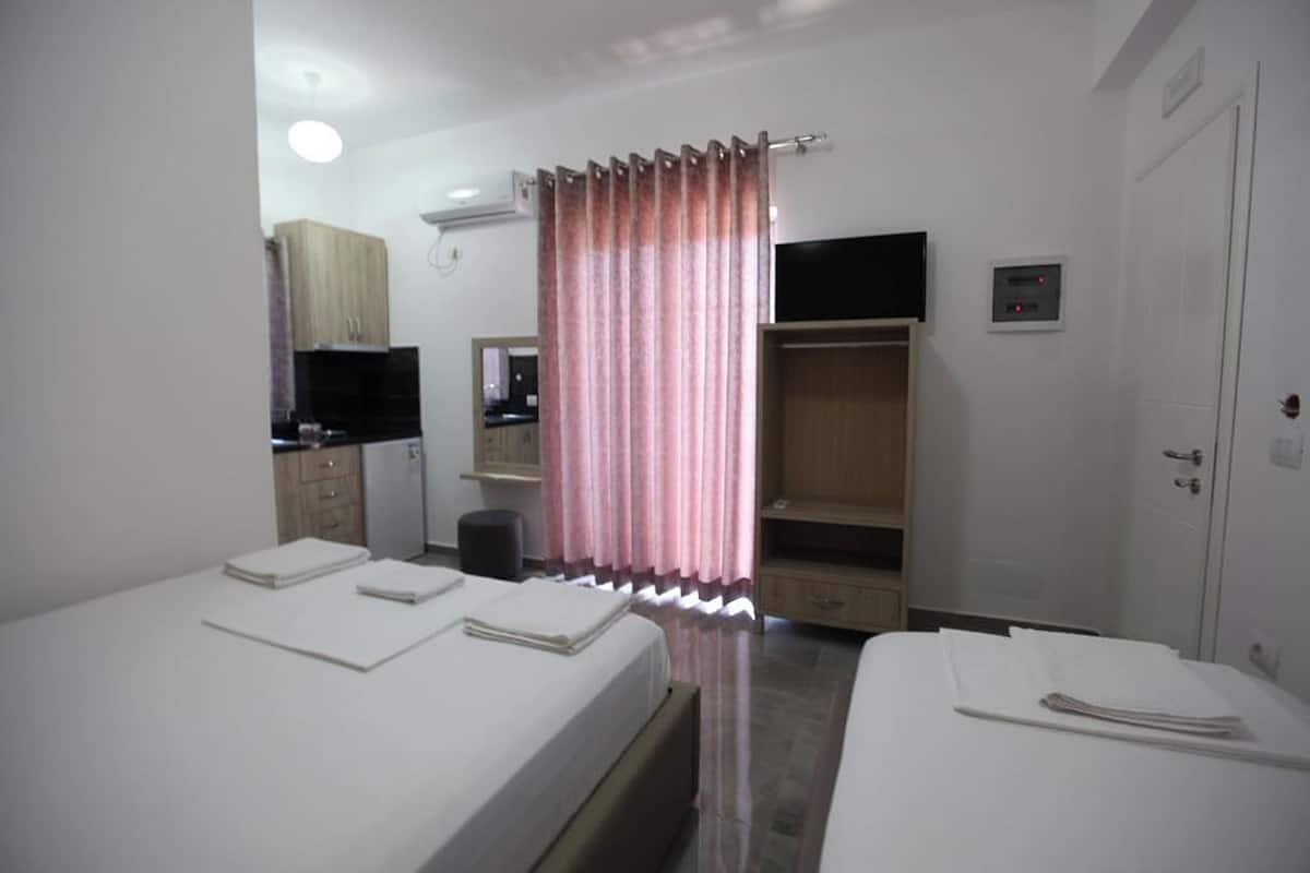 A hotel room with two beds, a television, a wardrobe, and a mirror.