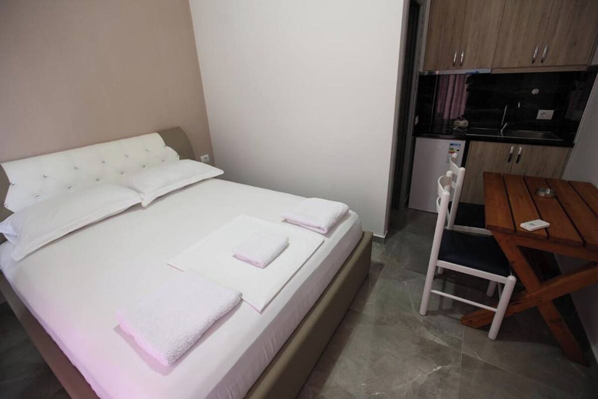 A bedroom with a bed, a small table, and a chair.