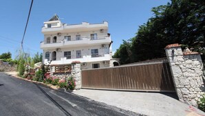 A multi-story building with a stone facade, a gated entrance, and a clear sky. - Vila Anhel (Ksamil)