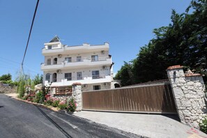 A multi-story building with a stone facade, a gated entrance, and a clear sky. - Vila Anhel (Ksamil)