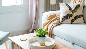 En hyggelig stue med sofa, et sofabord med en plante og en lampe.