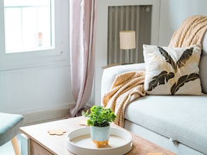 Ein gemütliches Wohnzimmer mit einer Couch, einem Beistelltisch mit Pflanze und einer Lampe.
