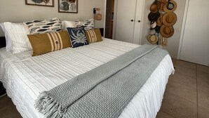 Un dormitorio ordenado con una cama grande, una lámpara de techo y adornos en la pared, incluyendo estrellas de mar y sombreros.