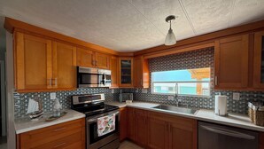 Una cocina con armarios de madera, un microondas de acero inoxidable, una estufa y un lavavajillas.
