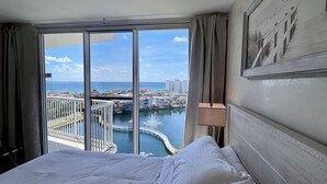 A hotel room with a large bed, a view of a marina, and a cityscape.