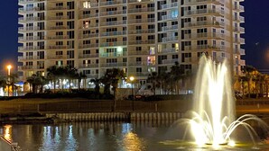 A multi-story hotel with balconies, a fountain, and a waterfront view.