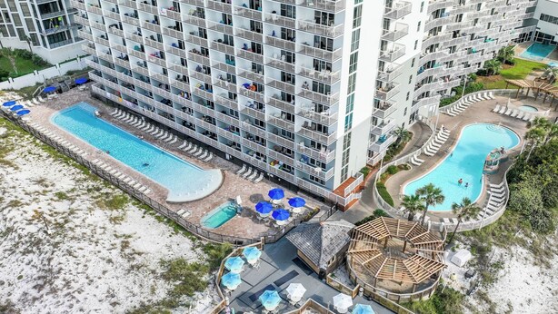 A high-rise hotel with multiple balconies, a central swimming pool, and a separate pool area.