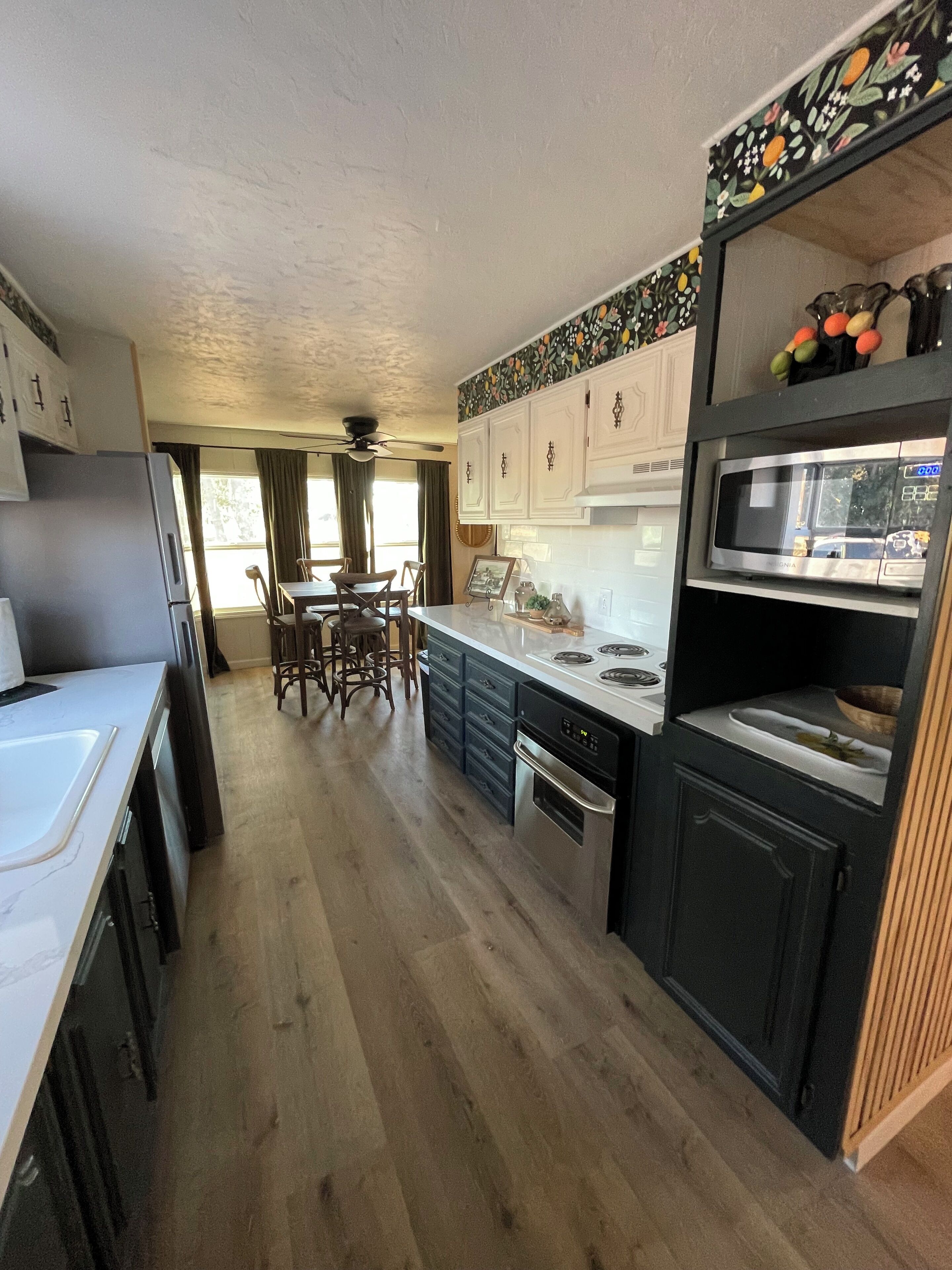 A compact kitchen with a refrigerator, stove, microwave, and wooden cabinets.