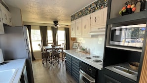 Una cocina compacta equipada con refrigerador, estufa, microondas y gabinetes de madera.