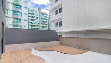 Terraço no telhado com deck de madeira e parede cinza.