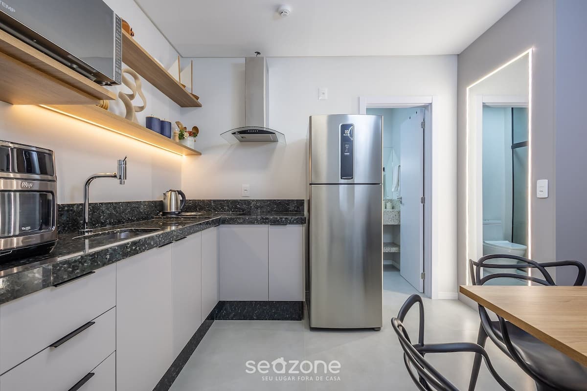 A modern kitchen with a stainless steel refrigerator, a built-in oven, and a granite countertop.