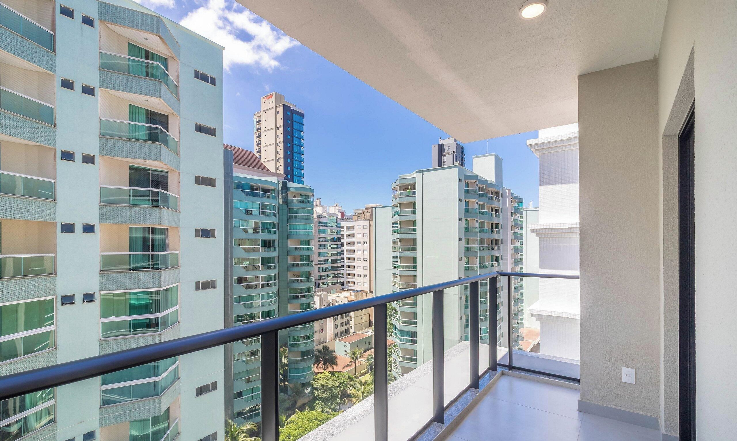 A high-rise residential building with multiple balconies, large windows, and a clear view of the surrounding urban area.