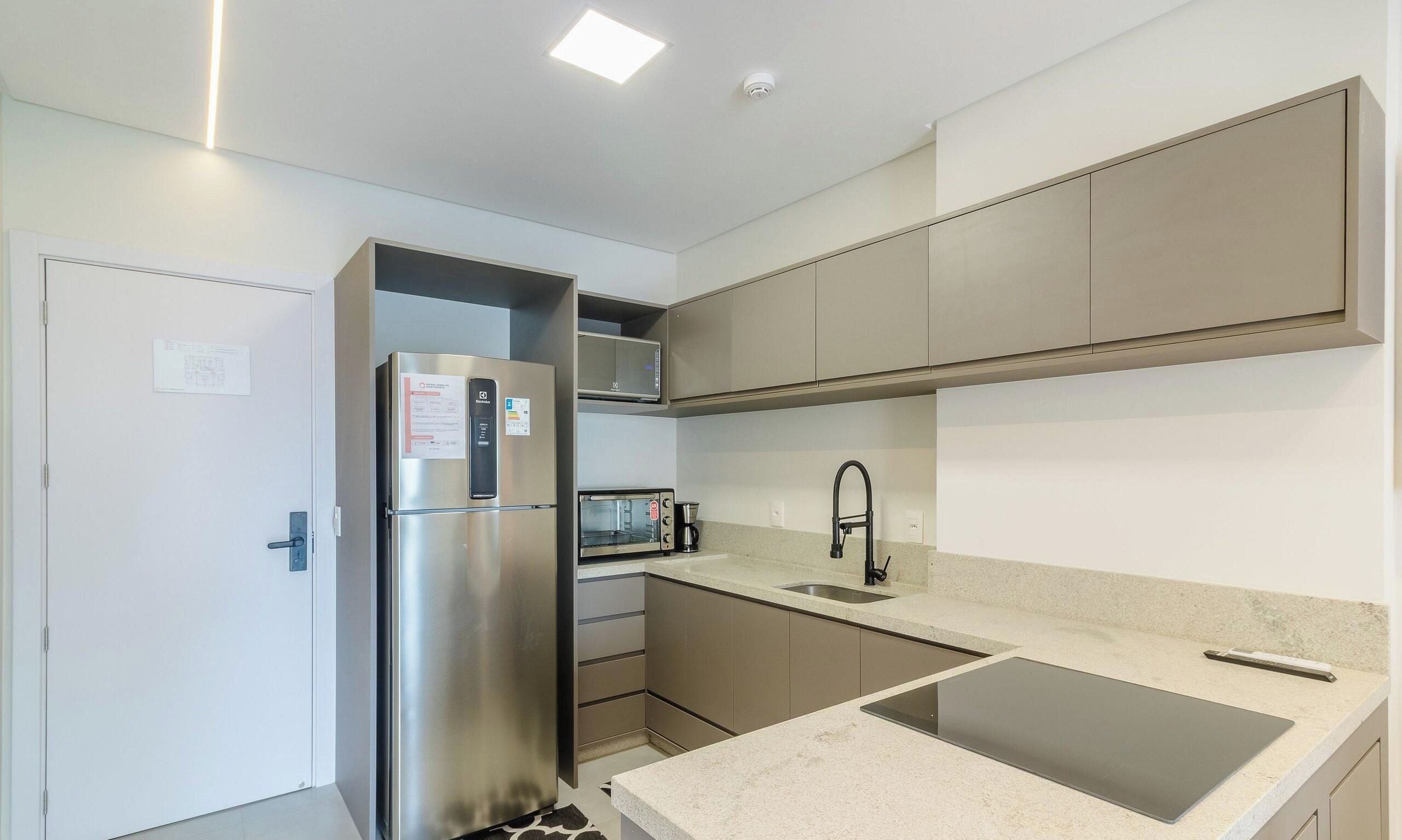 A modern kitchen with a built-in refrigerator, microwave, and toaster.