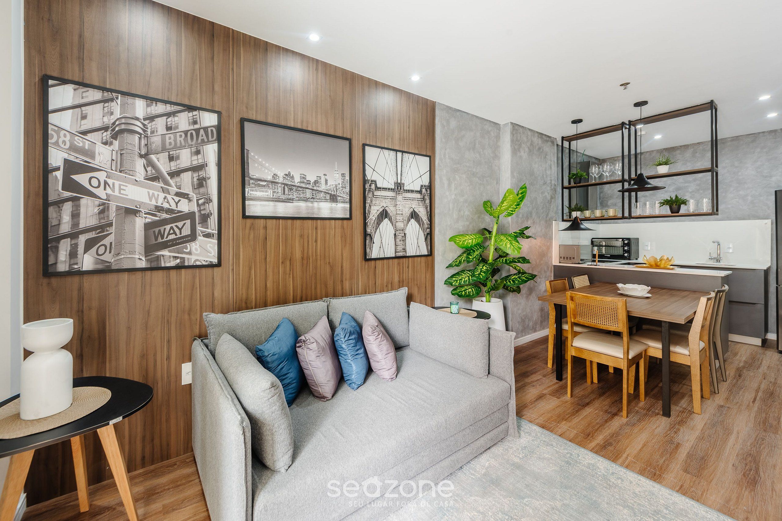 Una sala de estar moderna con sofá, mesa de comedor y zona de cocina.