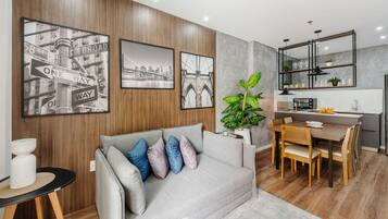 Una sala de estar moderna con sofá, mesa de comedor y zona de cocina.