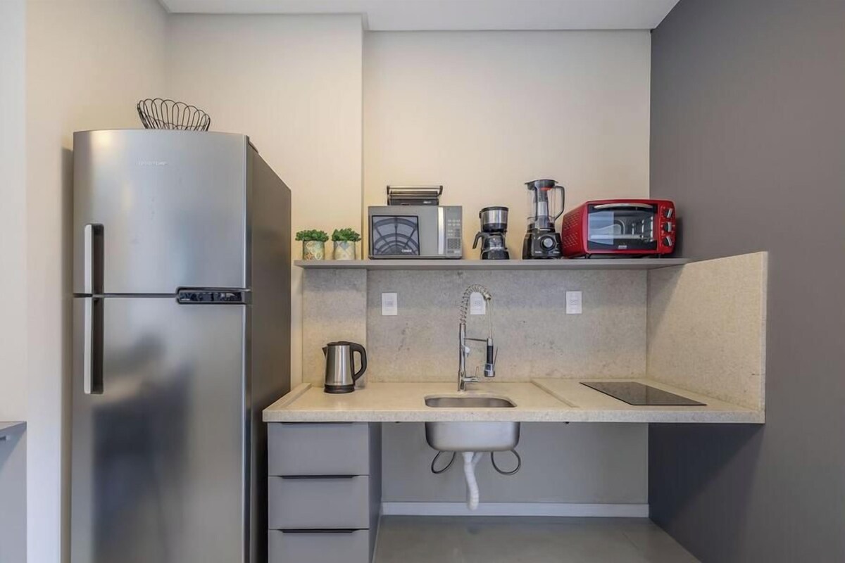 A compact kitchen with a refrigerator, microwave, coffee maker, toaster, and sink.