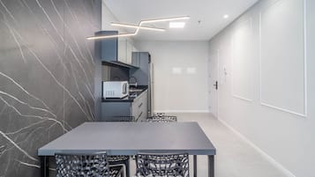 Una cocina moderna con salpicadero de mármol oscuro, microondas integrado y una lámpara elegante.