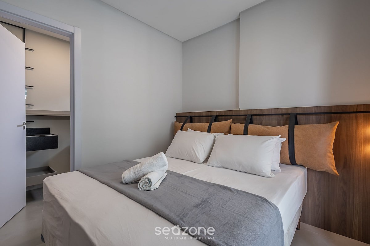 A hotel room with a bed, a wooden headboard, a built-in shelf, and a closet with sliding doors.