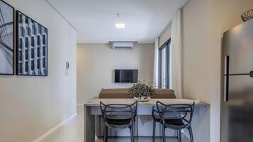Una cocina moderna con refrigerador integrado, un televisor de pantalla plana montado en la pared y un comedor con dos sillas y una mesa.