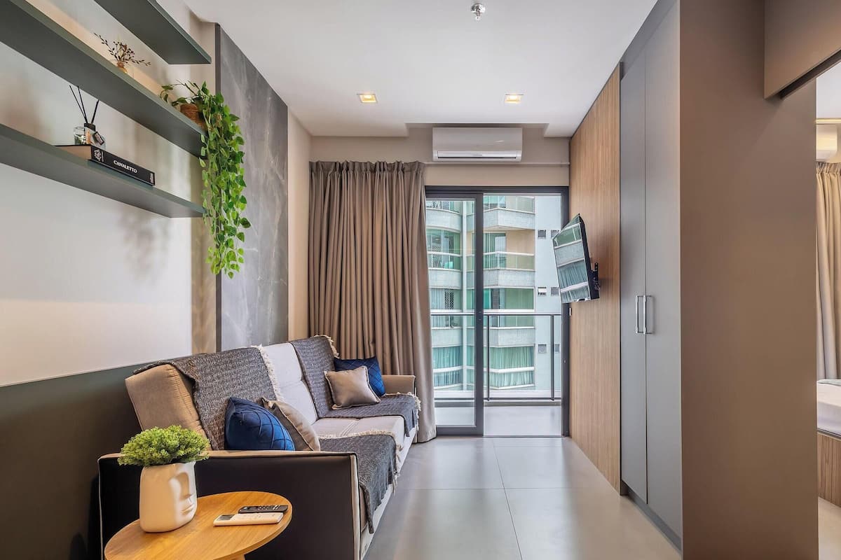 A modern living room with a sofa, a small table, and a TV mounted on the wall.