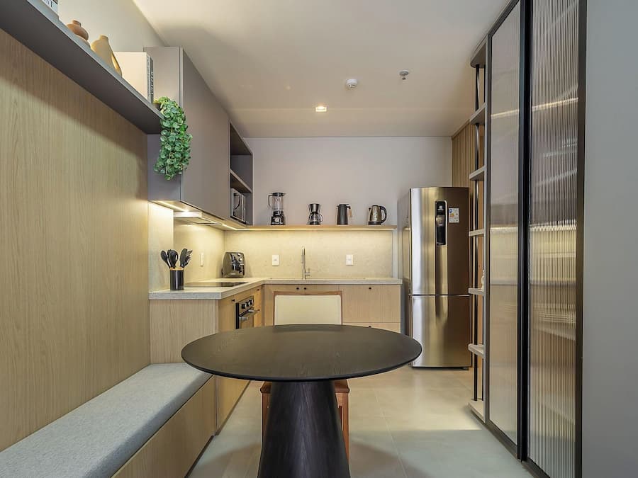 A modern kitchen with a round table, built-in appliances, and a hanging plant.