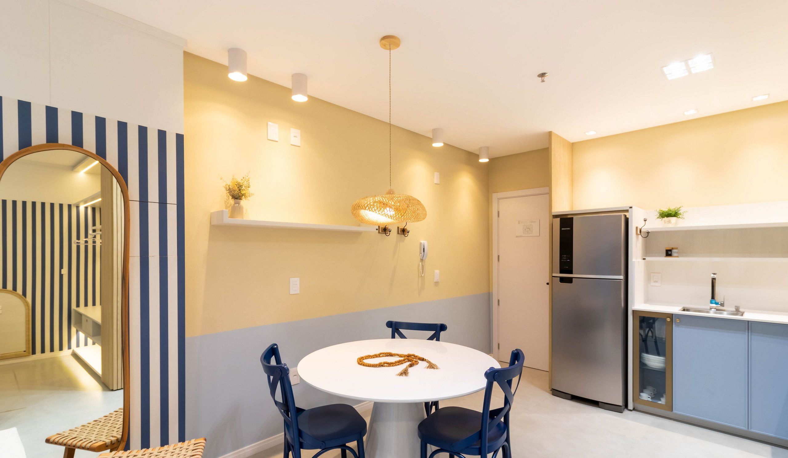 Una cocina moderna con una mesa redonda, sillas, un refrigerador y una lámpara colgante.